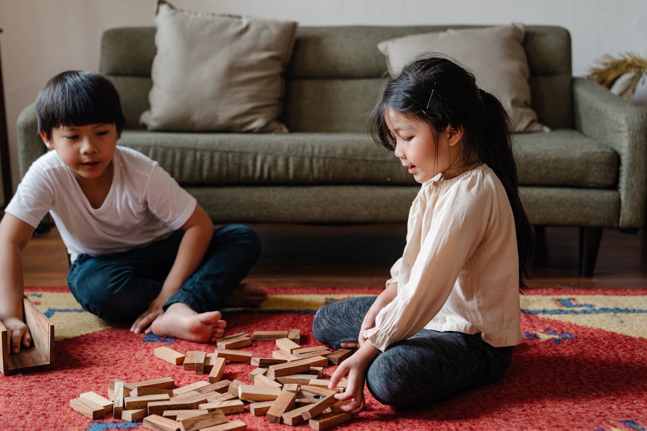 Adorable ethnic kids playing jenga at home on floor